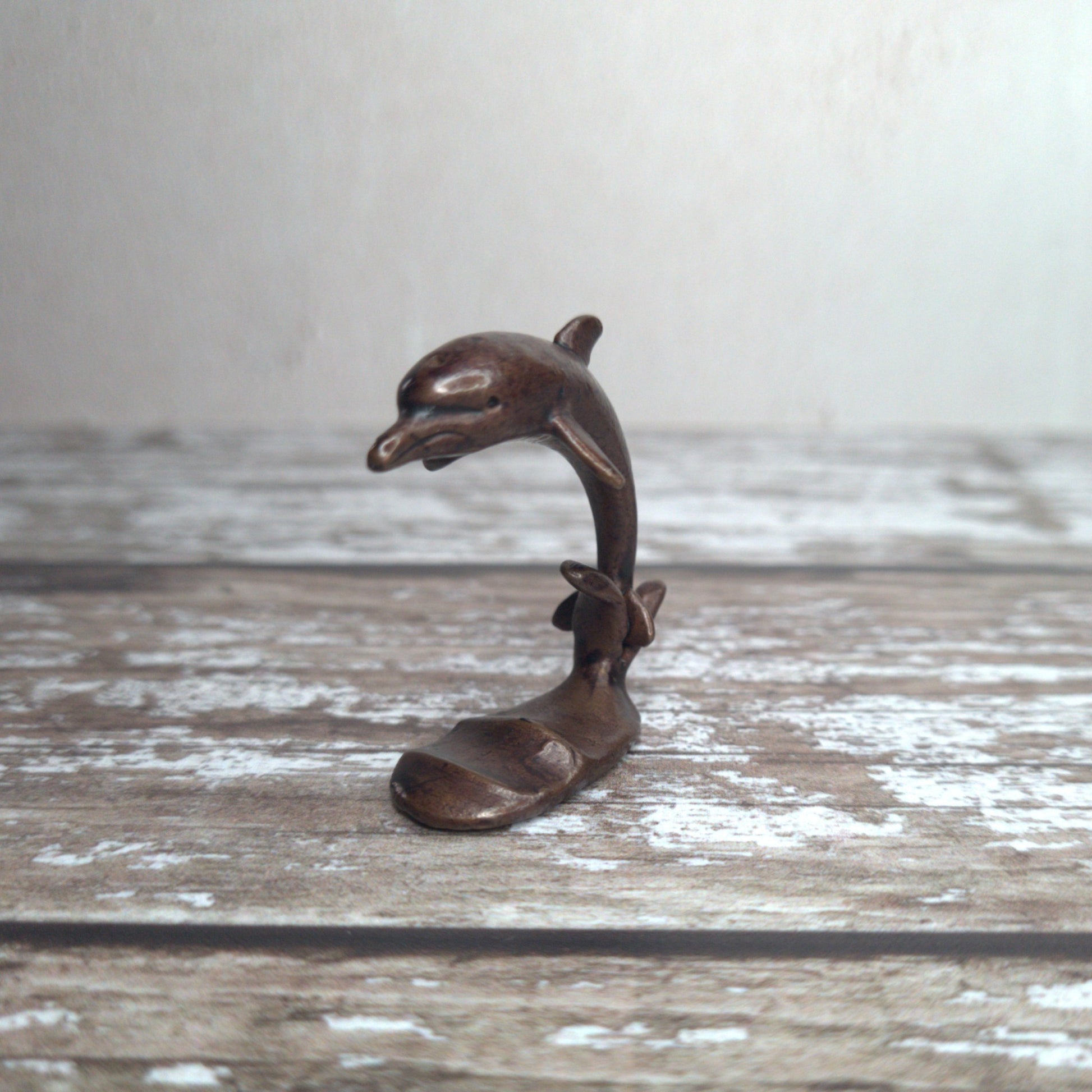 Miniature bronze dolphin sculpture standing on wave base, by David Meredith at Alcove Art