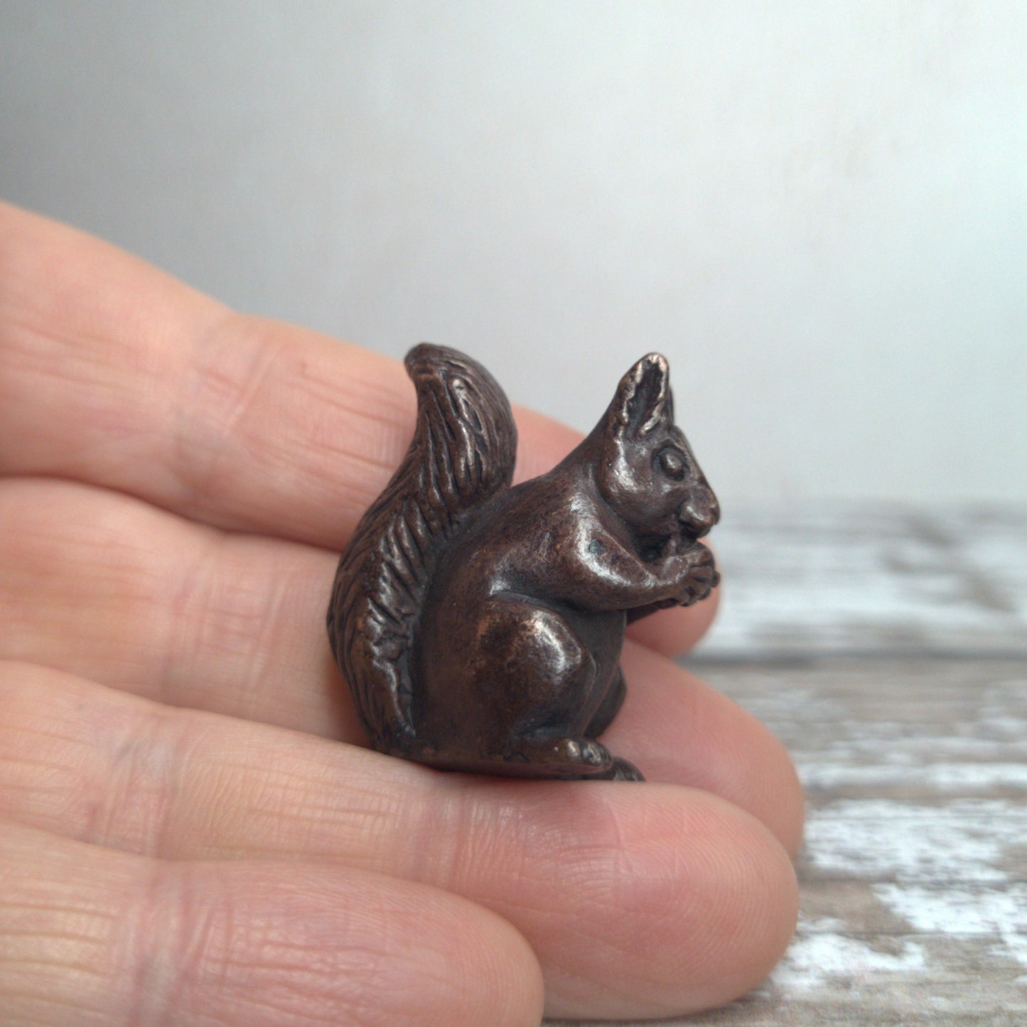 Miniature bronze squirrel sculpture held in hand to show scale, by David Meredith at Alcove Art